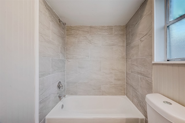 bathroom with toilet and tiled shower / bath