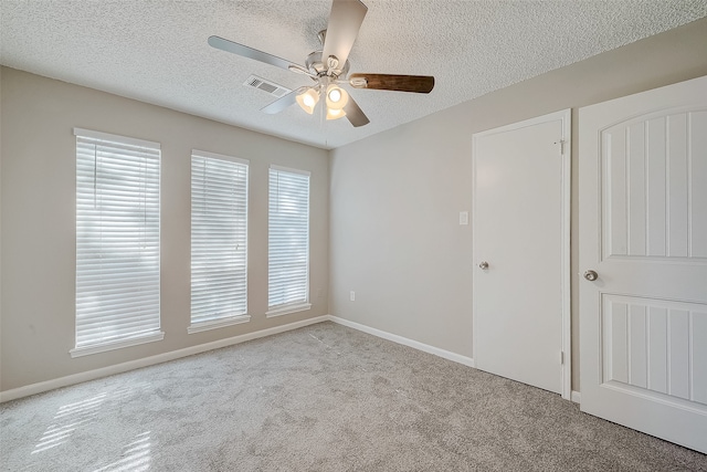 unfurnished room featuring a textured ceiling, light colored carpet, and ceiling fan