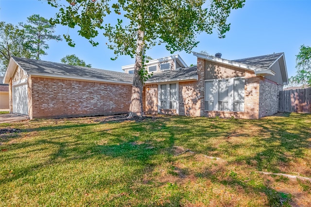 rear view of house featuring a lawn and a garage