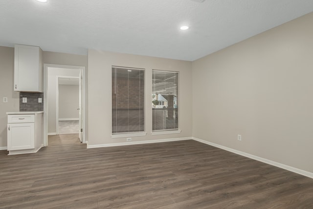 unfurnished room featuring a textured ceiling and dark hardwood / wood-style flooring