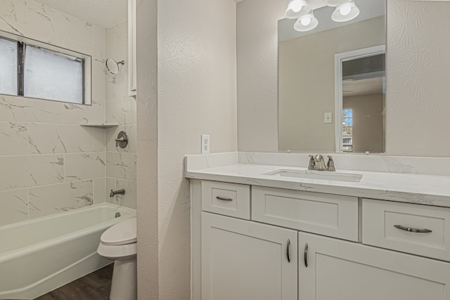 full bathroom with plenty of natural light, toilet, tiled shower / bath, and vanity