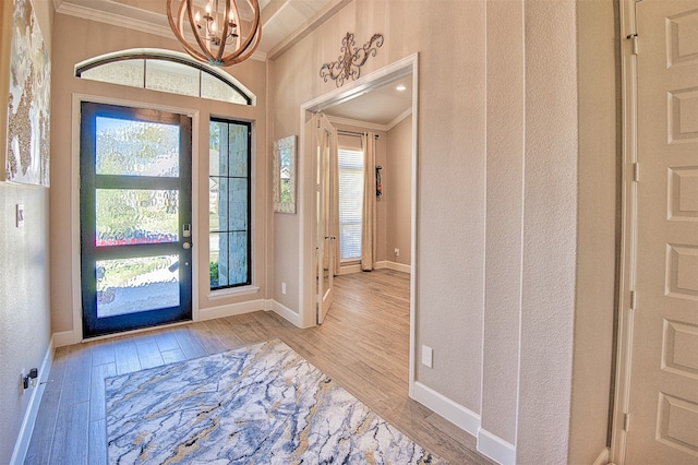 entryway with light hardwood / wood-style floors, an inviting chandelier, and ornamental molding