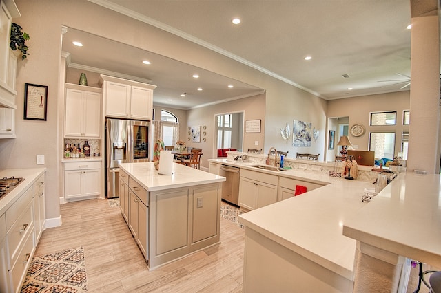 kitchen featuring sink, stainless steel appliances, light hardwood / wood-style flooring, kitchen peninsula, and a spacious island