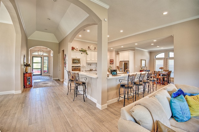 kitchen with a kitchen bar, stainless steel appliances, white cabinetry, and a healthy amount of sunlight