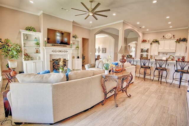 living room with ceiling fan, ornamental molding, and light hardwood / wood-style flooring