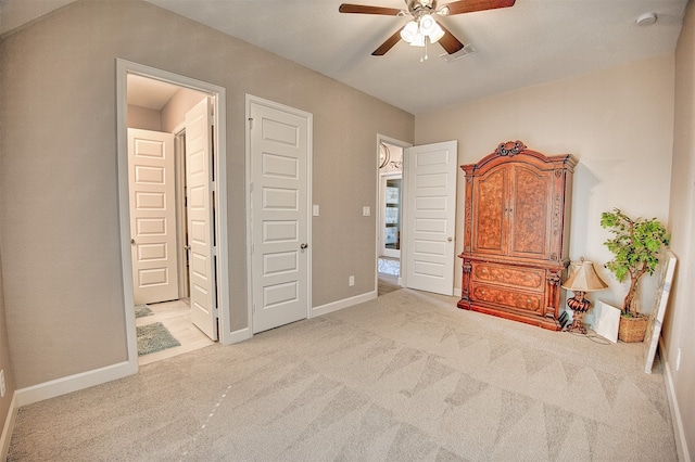 unfurnished bedroom featuring ceiling fan, light carpet, and connected bathroom