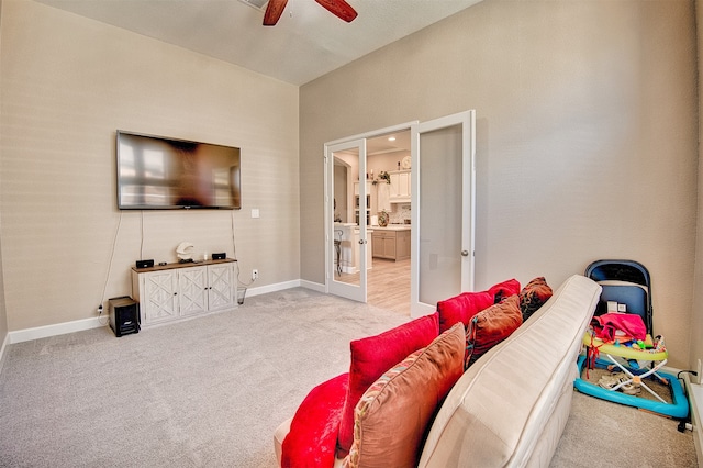 carpeted living room with ceiling fan and french doors