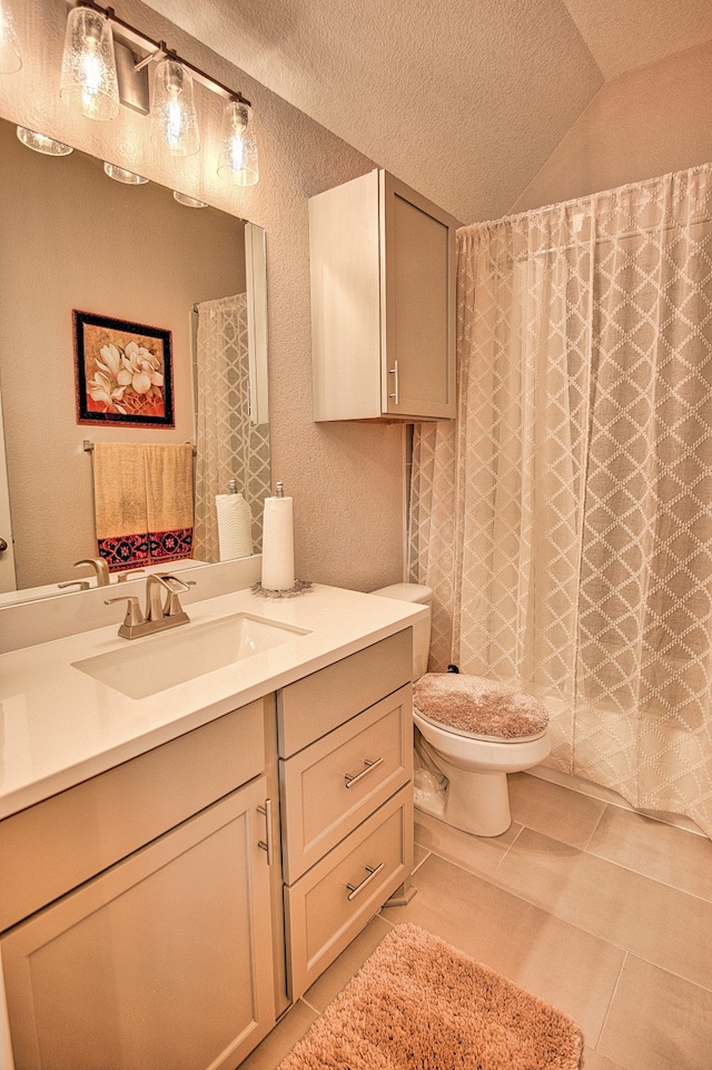 bathroom with tile patterned floors, a textured ceiling, lofted ceiling, toilet, and vanity