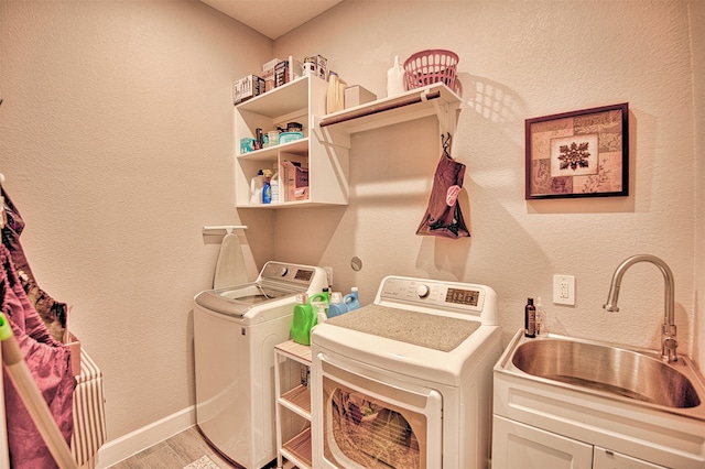 laundry area with washing machine and dryer, sink, cabinets, and light hardwood / wood-style flooring