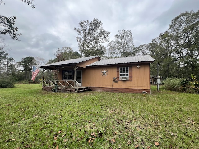 rear view of house with cooling unit, covered porch, and a yard