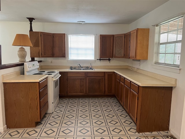 kitchen featuring pendant lighting, a healthy amount of sunlight, sink, and white electric stove