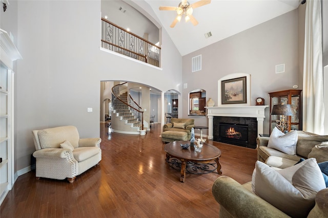 living room with ornate columns, ceiling fan, a high ceiling, and hardwood / wood-style flooring