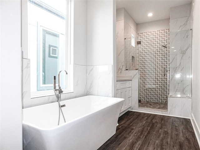 bathroom featuring plus walk in shower, vanity, and hardwood / wood-style flooring