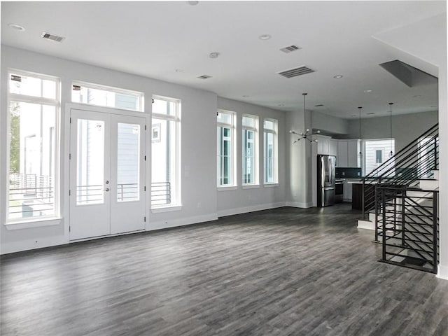 unfurnished living room featuring dark hardwood / wood-style flooring, a wealth of natural light, and french doors