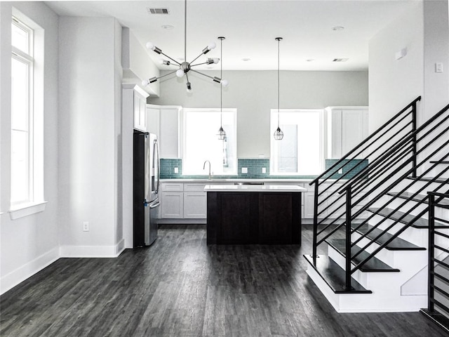 kitchen featuring stainless steel fridge, plenty of natural light, a center island, and decorative light fixtures