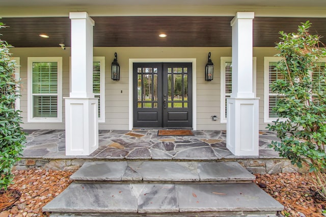 view of exterior entry featuring french doors and a porch