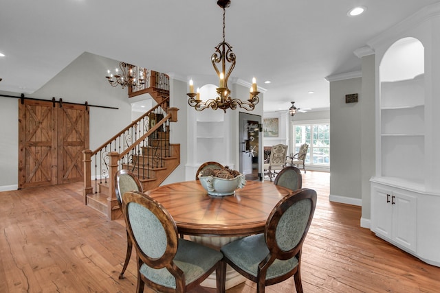 dining room featuring light wood-type flooring, ceiling fan with notable chandelier, crown molding, a barn door, and built in features