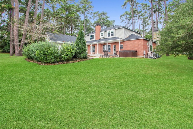 back of property with a yard and a hot tub