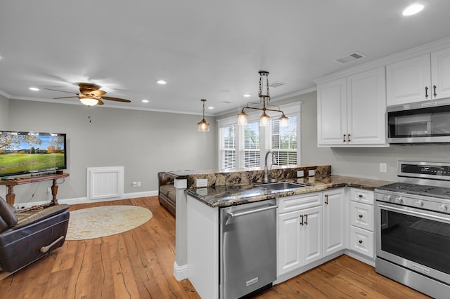 kitchen with pendant lighting, kitchen peninsula, sink, appliances with stainless steel finishes, and white cabinetry