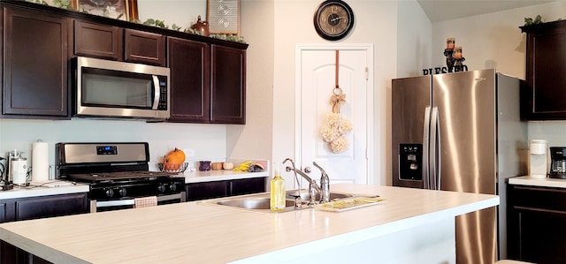 kitchen featuring dark brown cabinetry, stainless steel appliances, a kitchen island with sink, and sink