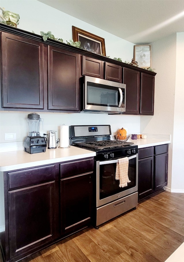 kitchen featuring dark brown cabinetry, appliances with stainless steel finishes, and light hardwood / wood-style flooring