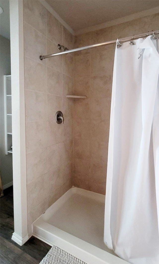 bathroom with wood-type flooring, walk in shower, and ornamental molding