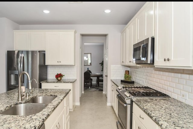 kitchen with light stone countertops, sink, stainless steel appliances, decorative backsplash, and white cabinets