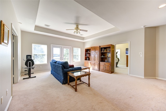 carpeted living room featuring ceiling fan, a raised ceiling, and french doors