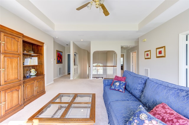 carpeted living room featuring ceiling fan and a tray ceiling