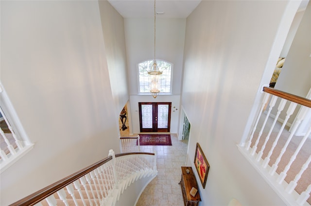 foyer with french doors, a towering ceiling, and a notable chandelier