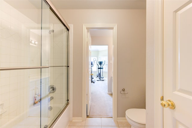 bathroom featuring tile patterned flooring, bath / shower combo with glass door, and toilet