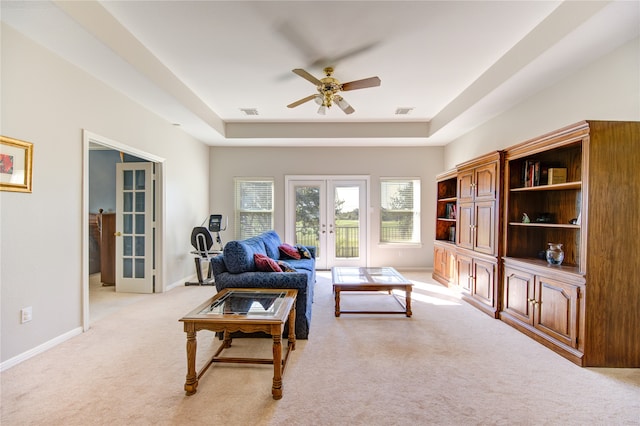 living room featuring ceiling fan, light carpet, a tray ceiling, and french doors