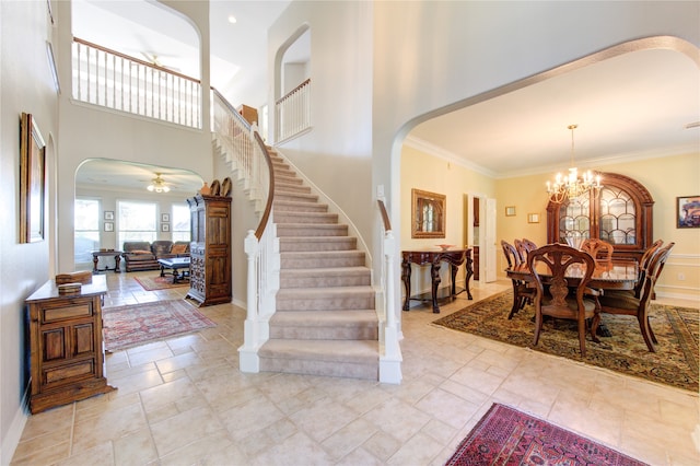 entrance foyer featuring a towering ceiling, ceiling fan with notable chandelier, and crown molding