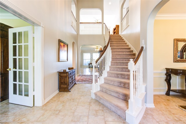 foyer entrance featuring crown molding and a towering ceiling