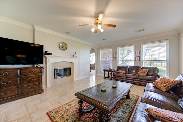 living room with a tile fireplace, ceiling fan, and ornamental molding