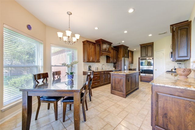 kitchen featuring backsplash, a chandelier, pendant lighting, a kitchen island, and appliances with stainless steel finishes