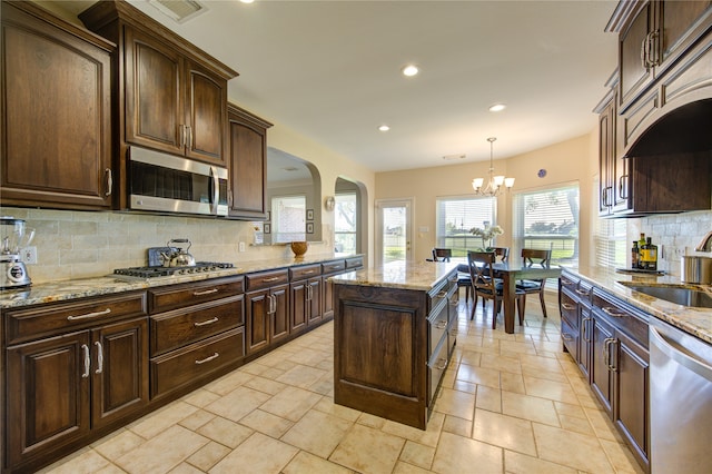 kitchen with sink, decorative light fixtures, decorative backsplash, dark brown cabinets, and stainless steel appliances