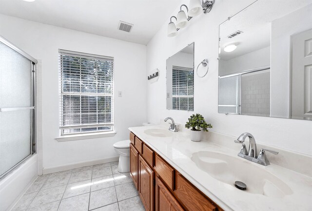 full bathroom featuring toilet, tile patterned floors, plenty of natural light, and combined bath / shower with glass door