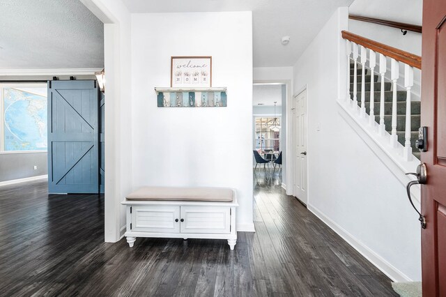 corridor featuring a textured ceiling, a barn door, and dark wood-type flooring