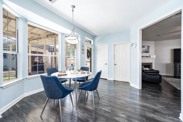 dining space featuring a wealth of natural light, a fireplace, and dark wood-type flooring