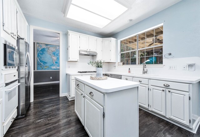 kitchen featuring sink, dark hardwood / wood-style floors, appliances with stainless steel finishes, a kitchen island, and white cabinetry