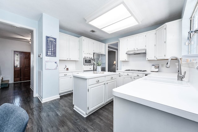 kitchen with sink, stainless steel appliances, a kitchen island, dark hardwood / wood-style floors, and white cabinets