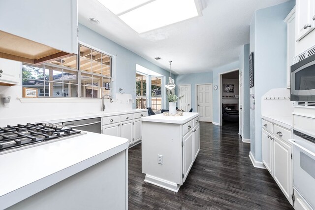 kitchen with a center island, white cabinets, dark hardwood / wood-style floors, decorative light fixtures, and stainless steel appliances