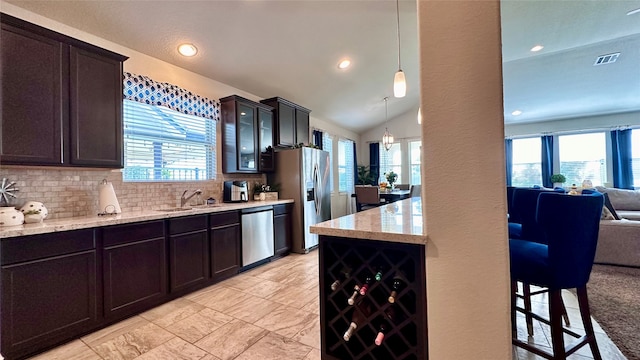 kitchen featuring plenty of natural light, decorative light fixtures, lofted ceiling, and appliances with stainless steel finishes