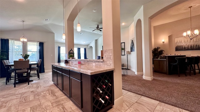 kitchen featuring light carpet, dark brown cabinetry, a wealth of natural light, and hanging light fixtures