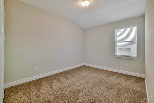 carpeted empty room featuring lofted ceiling