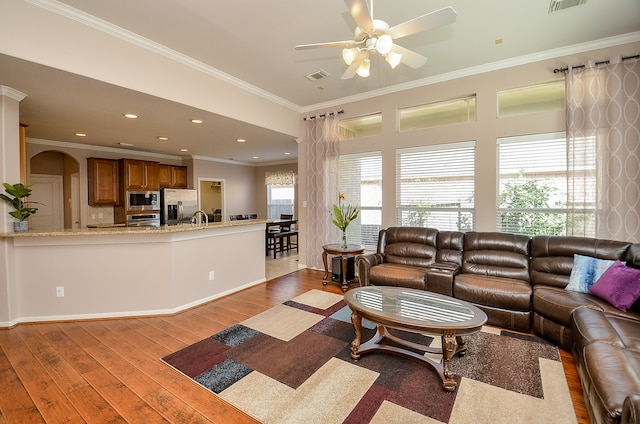 living room with light hardwood / wood-style floors, ceiling fan, ornamental molding, and sink