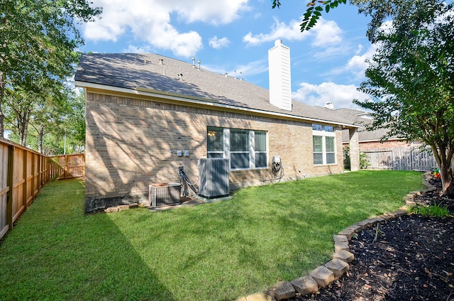 rear view of property featuring a yard and central AC