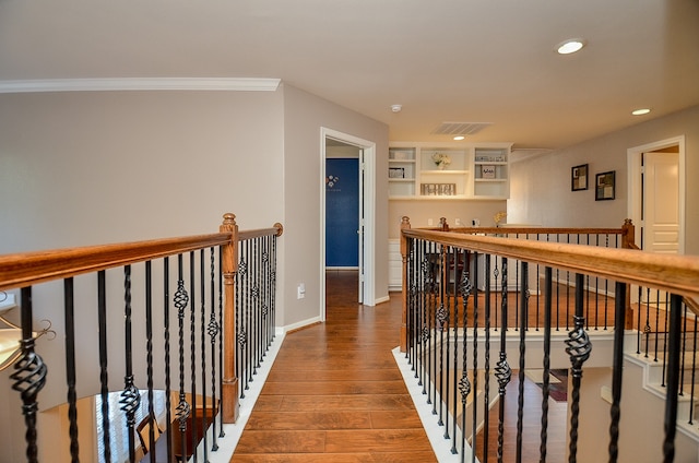 hall featuring built in features, wood-type flooring, and ornamental molding