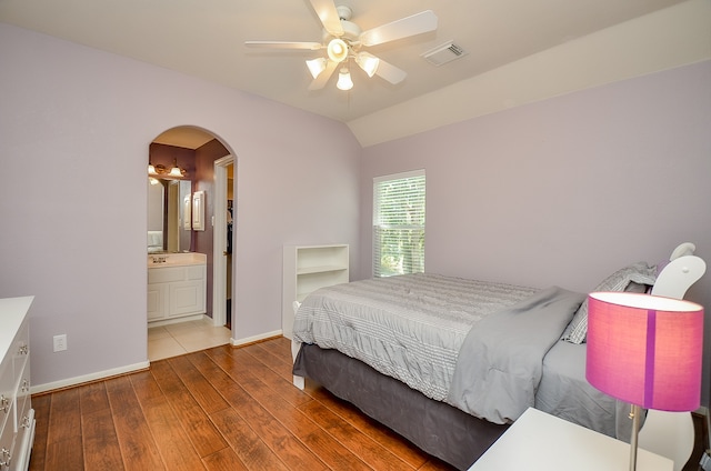 bedroom featuring ceiling fan, lofted ceiling, dark wood-type flooring, and connected bathroom